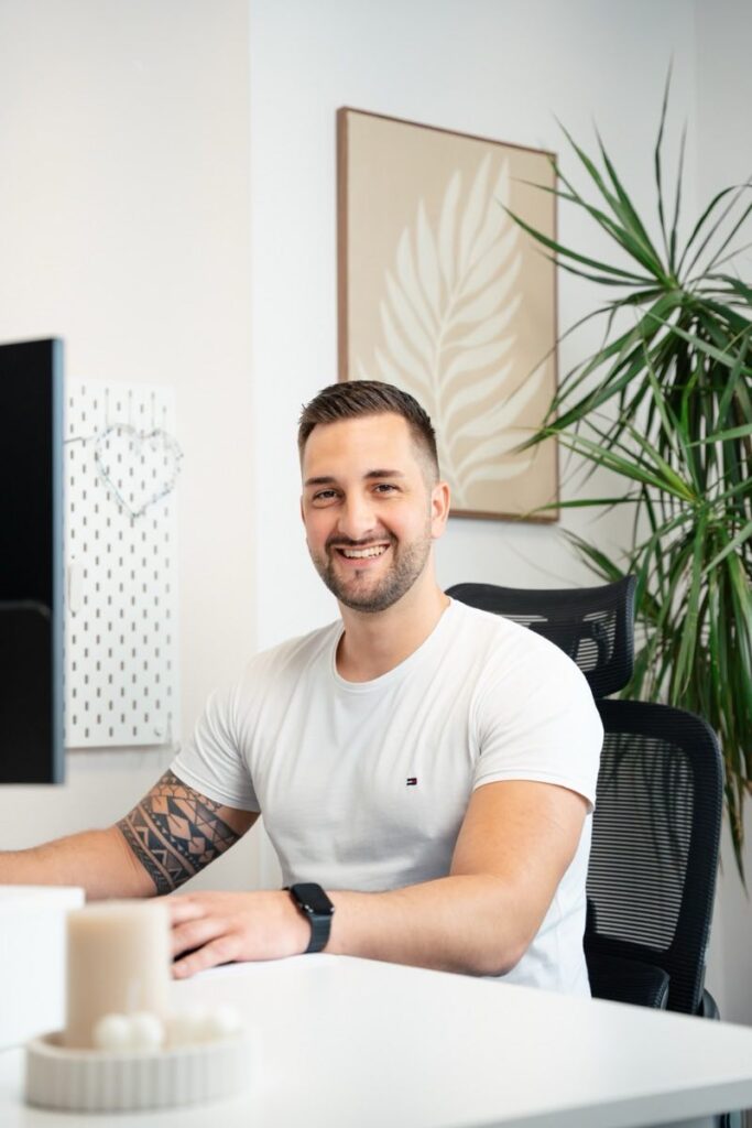 Mitarbeiter Kevin Rose lächelt am Schreibtisch im modernen Büro des Seniorenzentrums Lichtenberg